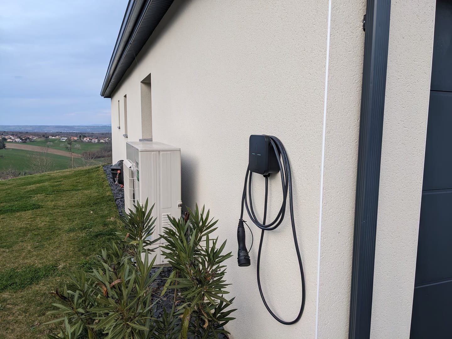 Borne Tesla noire murale avec câble enroulé sur façade maison moderne quartier Versailles